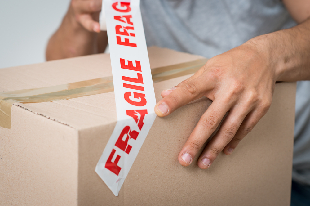 Close,up,of,a,man,packing,cardboard,box,with,sellotape