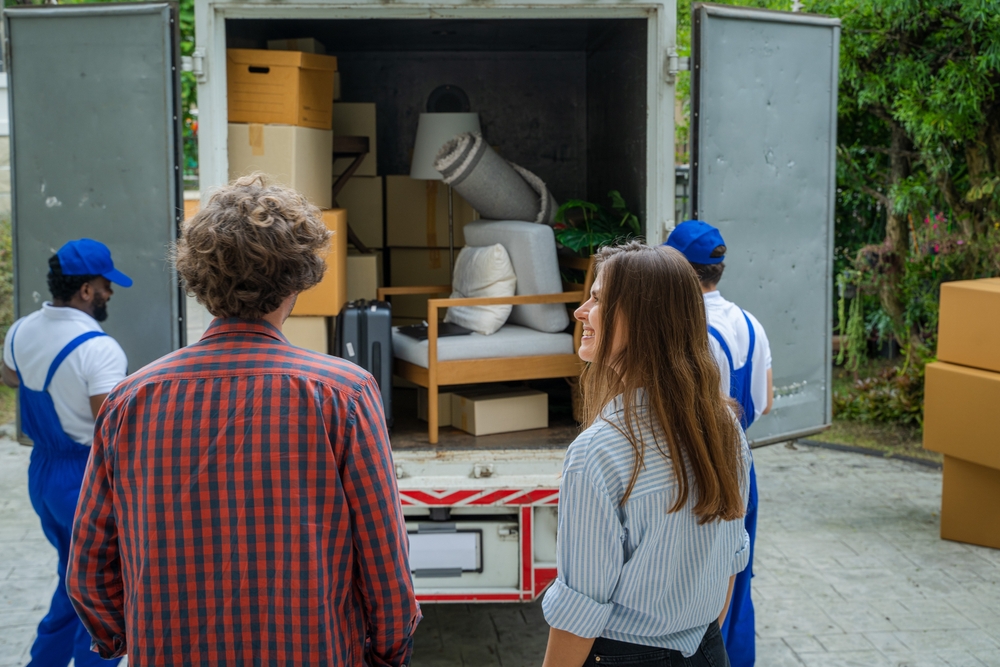 Happy,couple,with,moving,boxes,at,new,house,moving,company,employee