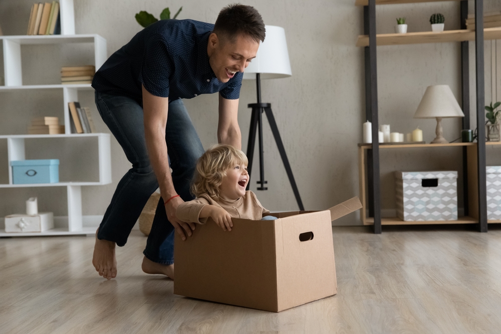 Cheerful,excited,dad,shifting,moving,cardboard,box,with,happy,screaming